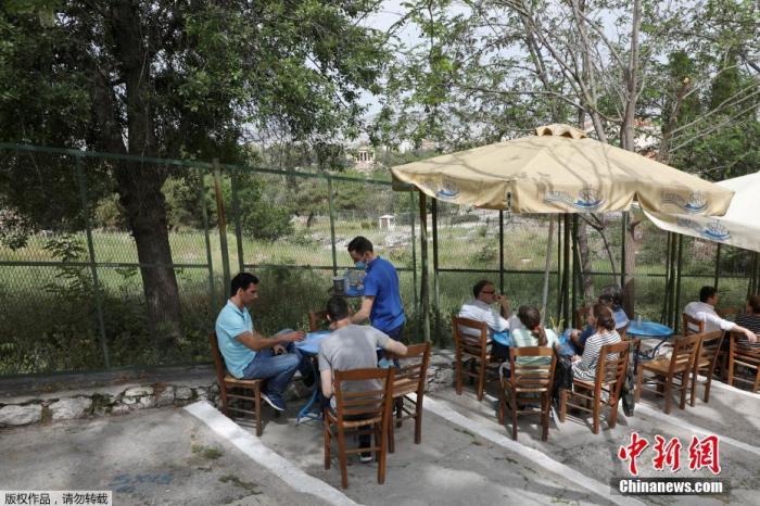 当地时间5月3日，希腊雅典，人们在一家露天咖啡享用饮品。在经历了将近6个月的封锁措施后，希腊的餐厅和咖啡馆自5月3日开始部分恢复营业。由于相关防疫措施仍在生效，希腊政府仅允许餐馆和咖啡馆在户外区域接待顾客。